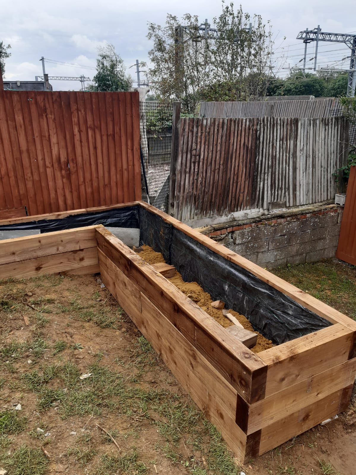 Timber raised bed being constructed around the edge of the garden